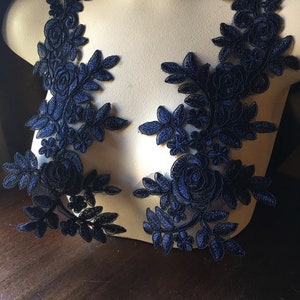 May include: Two navy blue lace appliques with floral designs. The appliques feature delicate leaves and roses.