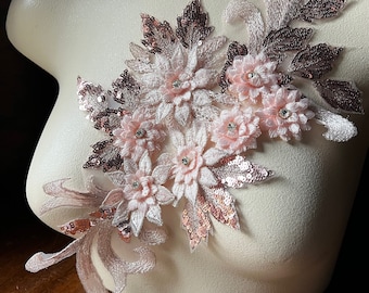 Puede incluir: Una delicada aplicación floral con lentejuelas y cuentas de color rosa y oro rosa. La aplicación presenta un grupo de flores con detalles intrincados y un diseño de vid fluida.