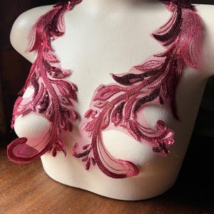 Könnte beinhalten: Zwei burgunderfarbene Spitzenapplikationen mit Pailletten, perfekt, um jedem Kleidungsstück einen Hauch von Eleganz zu verleihen.