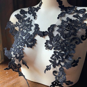 May include: Black floral lace applique with delicate details. This lace trim is perfect for adding a touch of elegance to any project.
