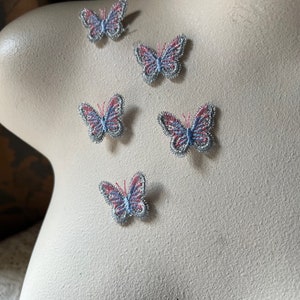 Puede incluir: Cinco apliques de mariposa plateadas y rosas con un acabado brillante.