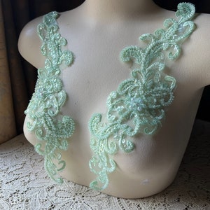 May include: Two light green lace appliques with pearl-like beads, perfect for adding a touch of elegance to a garment.