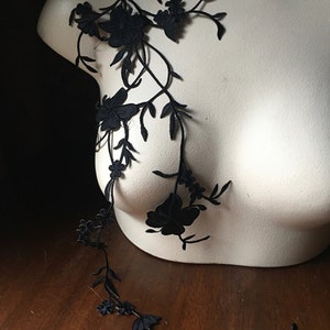 May include: Black floral lace applique with delicate flowers and vines. This lace trim is perfect for adding a touch of elegance to any project.