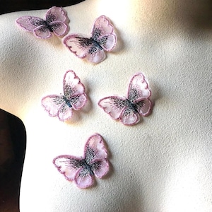 May include: Five pink and black embroidered butterfly appliques. The butterflies are delicate and have a sheer fabric texture.