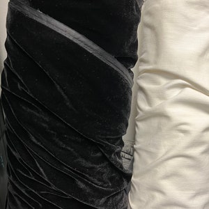 May include: Two rolls of fabric, one black velvet and one white, side by side.