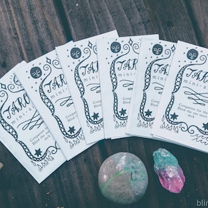 May include: A stack of white tarot mini-zines with black ink illustrations and text. The text reads "Tarot mini-zine" and "Companion for the Blind the Sun tarot deck".