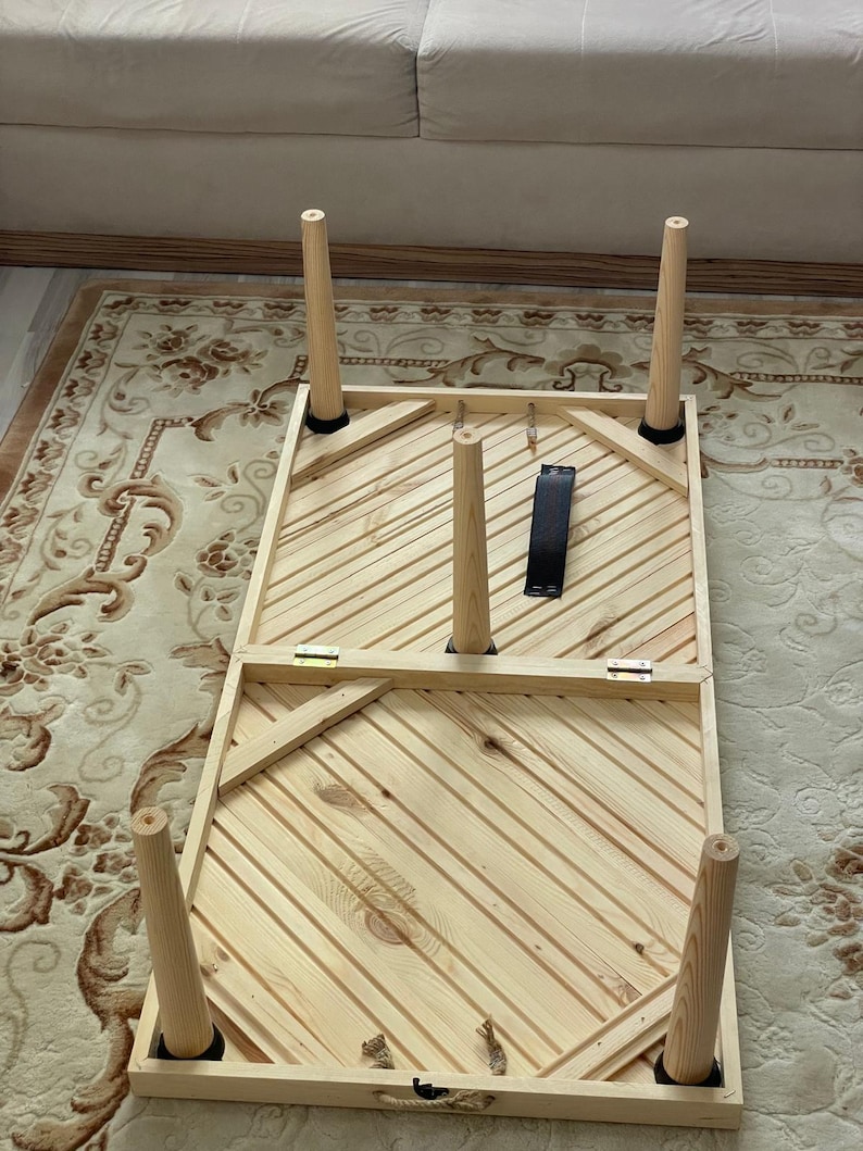 May include: A wooden table with a striped top and six legs. The table is folded in half and the legs are folded up.
