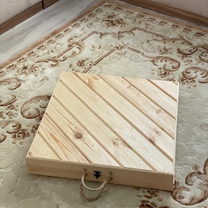 May include: A wooden storage box with a hinged lid and rope handles. The lid has a diagonal pattern of wood planks.
