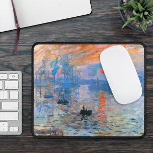May include: A rectangular mousepad featuring a colorful impressionist painting of a harbor scene with boats, water reflections, and a vibrant sunset. A white computer mouse rests on the pad. The pad has a black border.