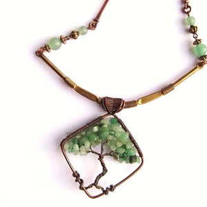 May include: A copper wire necklace with a green stone tree pendant. The tree is made of wire and has green stones for leaves. The necklace is made of copper wire and has a brass chain.