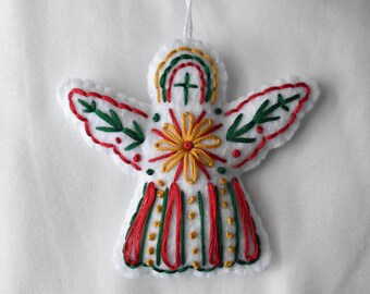 May include: White felt angel ornament with embroidered details. The angel features red, green, and yellow stitching, including a floral design on the chest and a rainbow above the head. The wings have green leaf patterns.