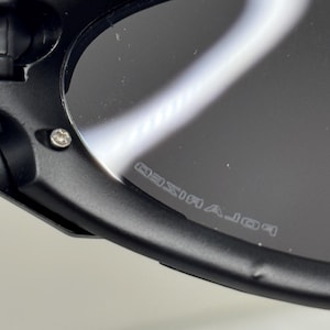 May include: Close-up of black sunglasses with polarized lenses. The frame is black and has silver rivets. The lenses are dark and reflect light. The word "POLARIZED" is printed on the lens.
