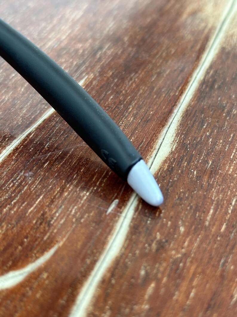 May include: A black stylus with a light blue tip. The stylus is angled towards the bottom right corner of the image. The background is a wooden surface with a brown color.