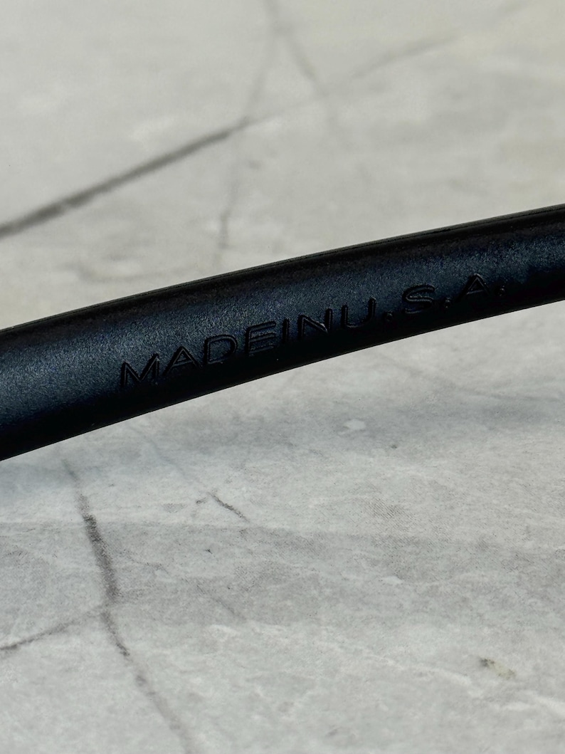 K&ouml;nnte beinhalten: Nahaufnahme eines schwarzen Objekts mit dem gepr&auml;gten Text "MADE IN U.S.A.". Das Objekt scheint Teil eines gr&ouml;&szlig;eren Gegenstands zu sein, m&ouml;glicherweise ein Werkzeug oder Zubeh&ouml;r. Der Hintergrund ist eine helle, strukturierte Oberfl&auml;che.