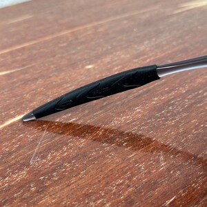 May include: Close-up of a black rubber temple tip for eyeglasses. The tip has a textured surface and the word "SPRIZE" is visible.