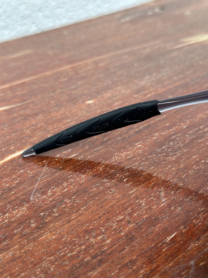May include: Close-up of a black rubber temple tip for eyeglasses. The tip has a textured surface and the word "SPRIZE" is visible.