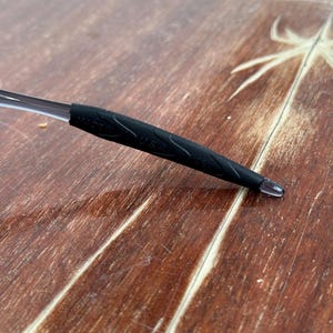 May include: Close-up of a black rubber temple tip for eyeglasses. The tip has the words "Made in USA" printed on it.