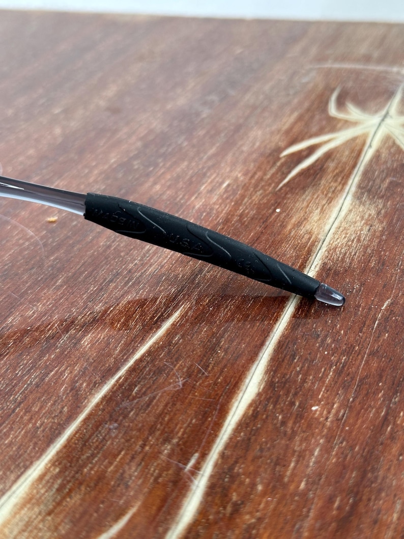 May include: Close-up of a black rubber temple tip for eyeglasses. The tip has the words "Made in USA" printed on it.