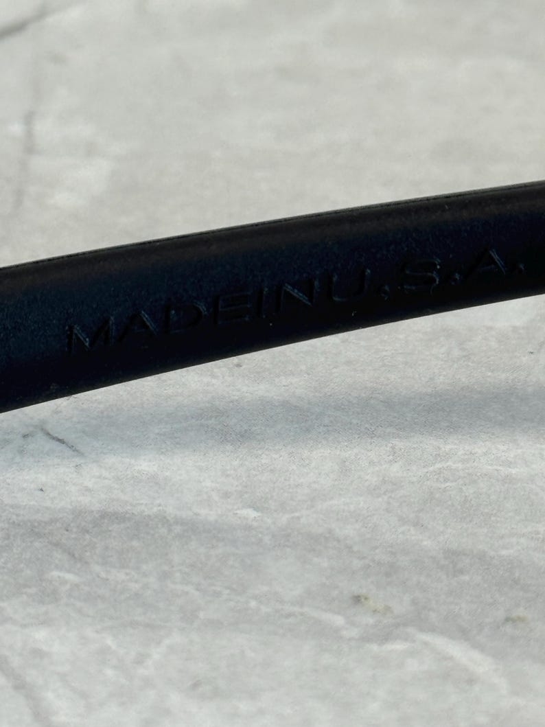 May include: Close-up of a black object with the text "MADE IN U.S.A." embossed on its surface. The object appears to be made of a smooth material, possibly leather or plastic.