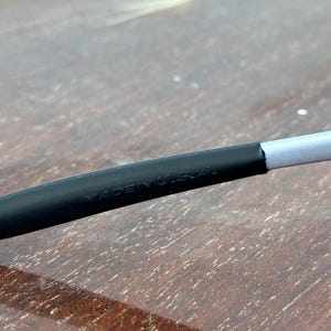 May include: Close-up of a black and gray object with the text "MADE IN U.S.A." printed on it. The object appears to be a part of a larger item, possibly eyewear or a similar accessory.