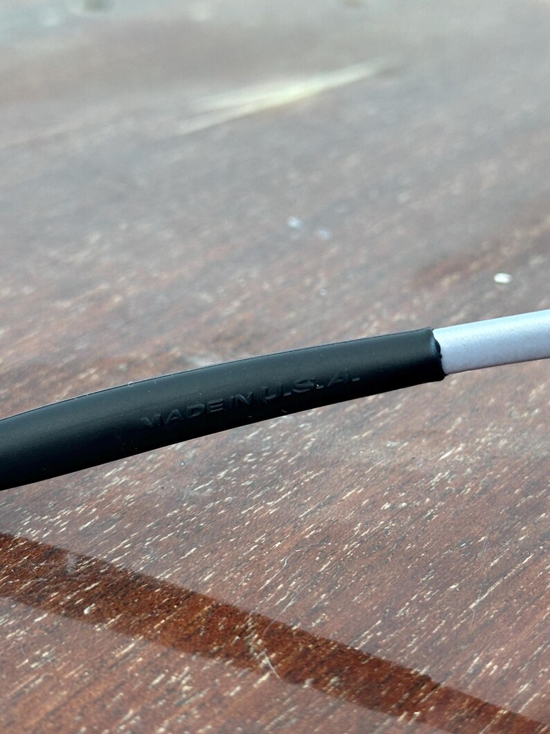 May include: Close-up of a black and gray object with the text "MADE IN U.S.A." printed on it. The object appears to be a part of a larger item, possibly eyewear or a similar accessory.