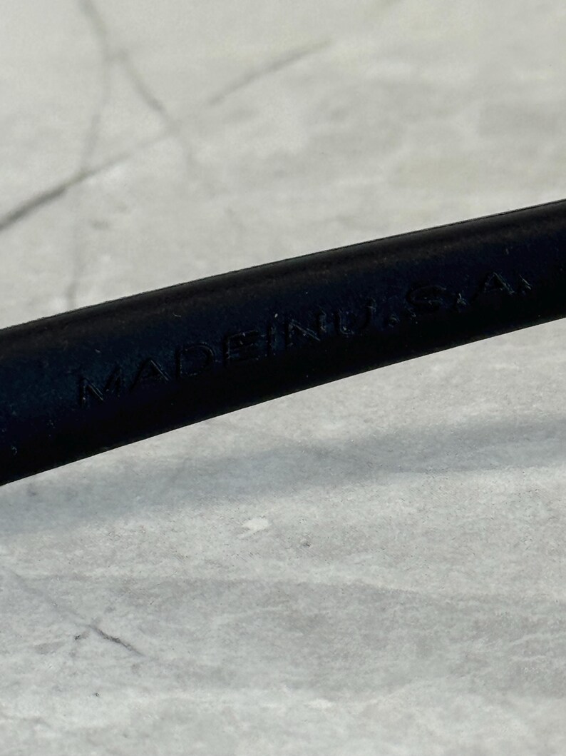 May include: Close-up of a black object with the text "MADE IN U.S.A." embossed on its surface. The object is set against a light grey background.