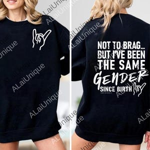 Può includere: Felpa nera con testo bianco e gesti delle mani. La parte anteriore presenta un gesto della mano. Il retro dice "NOT TO BRAG... BUT I'VE BEEN THE SAME GENDER SINCE BIRTH" in testo bianco.