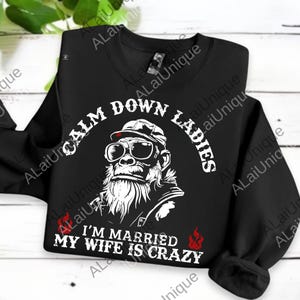 May include: Black sweatshirt featuring a gorilla wearing sunglasses and a hat. The text reads "CALM DOWN LADIES" and "I'M MARRIED MY WIFE IS CRAZY" in white. Two red flames are on the bottom.