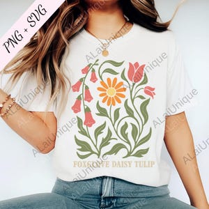 May include: White t-shirt with a floral design featuring orange daisies, pink tulips, and bell-shaped flowers. The design includes green leaves and the text "FOXGROVE DAISY TULIP". The shirt is labeled "PNG + SVG".
