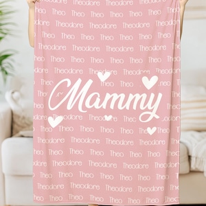May include: Pink fleece blanket with the word "Mammy" in white cursive lettering and two white hearts. The blanket is covered in the names "Theodore" and "Theo" in white text.