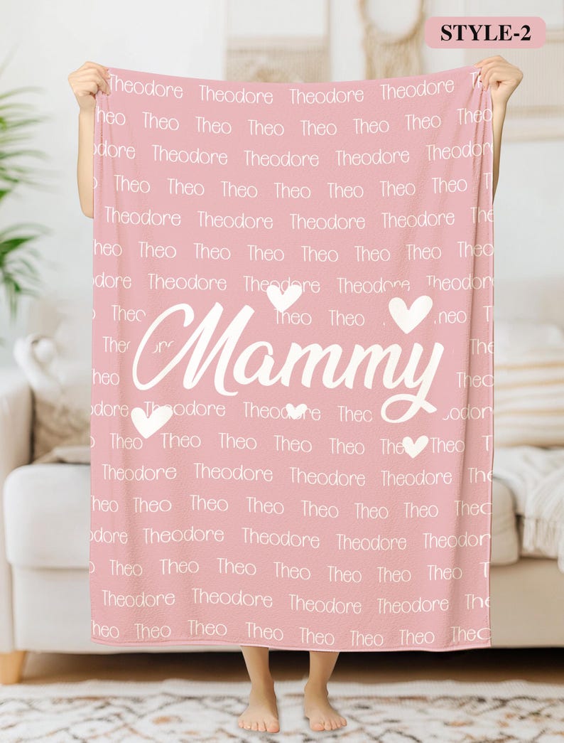 May include: Pink fleece blanket with the word "Mammy" in white cursive lettering and two white hearts. The blanket is covered in the names "Theodore" and "Theo" in white text.