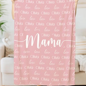 May include: A pink fleece blanket with the word "Mama" written in white cursive script. The blanket is covered in the name "Olivia" written in white script.
