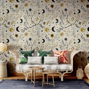 Pode incluir: Uma sala de estar com um sofá bege com almofadas e uma parede de cor creme com um papel de parede floral preto e dourado com luas, estrelas e sóis.