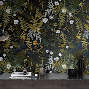 May include: Dark floral wallpaper featuring a dense pattern of green, yellow, and white flowers and foliage against a black background. A black desk lamp, books, and decorative items sit on a dark gray surface.