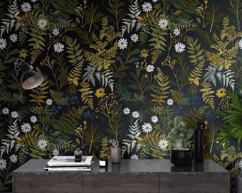 May include: Dark floral wallpaper featuring a dense pattern of green, yellow, and white flowers and foliage against a black background. A black desk lamp, books, and decorative items sit on a dark gray surface.