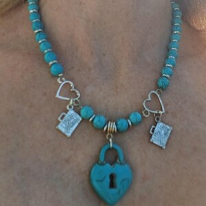Blauwe kralenketting met Love to Travel-bedel, blauw sleutelgathangslot en zilveren NY, London kofferbedels.