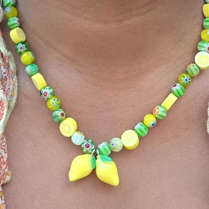 Prachtige citroen sieradenset. Perfect cadeau voor haar: ketting met bloemenkralen en bijpassende armband met citroenbedels en schattige schijfjes citrus.