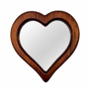 May include: A heart-shaped mirror with a dark brown wooden frame. The mirror's reflective surface is surrounded by the frame, creating a decorative wall hanging. The wood grain is visible, adding texture to the design.