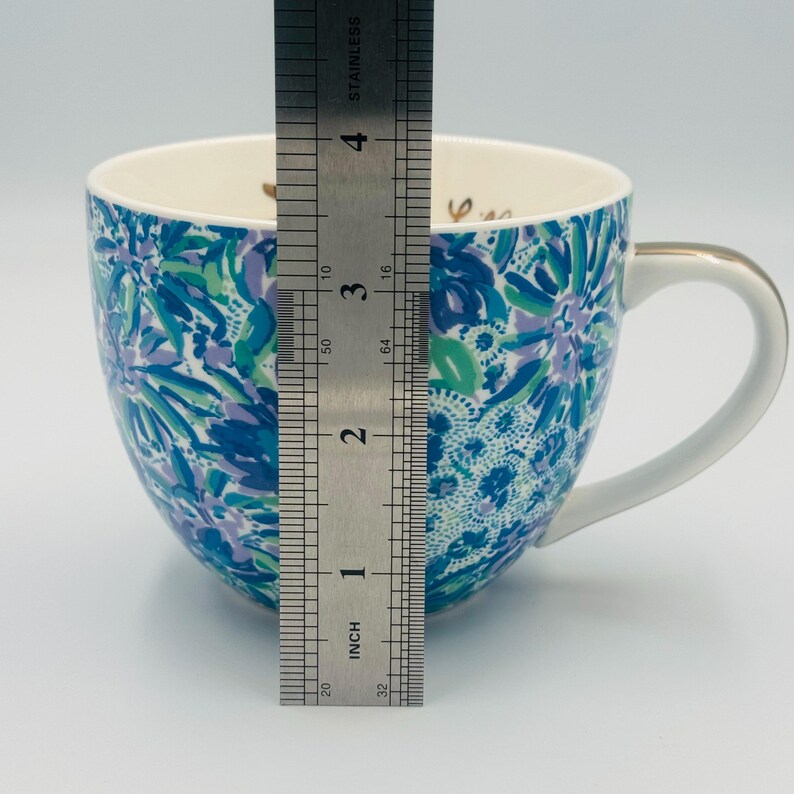 May include: A ceramic mug with a white handle and gold trim. The mug features a blue, green, and purple floral pattern. The mug is approximately 4 inches tall.