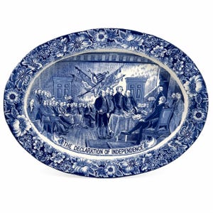 May include: Oval blue and white decorative plate featuring a historical scene of the signing of the Declaration of Independence. The plate has a floral border and the text "THE DECLARATION OF INDEPENDENCE".