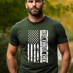 May include: Olive green t-shirt featuring a distressed American flag design. The flag is vertical with white stars and stripes, and the text "BEST. FUNCLE. EVER." is printed vertically on the right side. The shirt is made of a soft material.