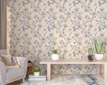 Puede incluir: Un interior de sala de estar con una pared beige claro con un patrón de papel tapiz floral. El papel tapiz tiene un patrón repetitivo de pequeñas flores amarillas claras con tallos azules y bayas rojas. Una mesa de café de madera con un acabado de madera clara se encuentra frente a la pared. Dos plantas en macetas están sobre la mesa. Un sillón gris con una almohada de cuadros está en primer plano.