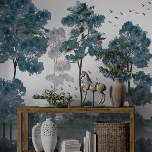 May include: A wooden console table displaying ornaments against a forest mural. The table features a horse statue, vases, plants, books, and a woven basket. The mural depicts trees in blue and grey, with birds in flight.