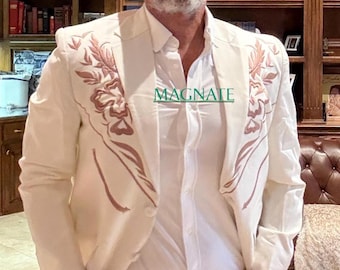 May include: Cream-colored blazer with embroidered floral design, paired with a white shirt and tan pants. A straw cowboy hat completes the look. The word "MAGNATE" is visible on the shirt.