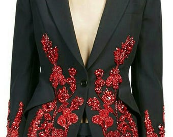 Könnte beinhalten: Ein schwarzer Blazer mit roter Blumen Stickerei. Der Blazer hat einen einzigen Knopfverschluss und lange Ärmel. Die Stickerei ist aus Pailletten und Perlen.