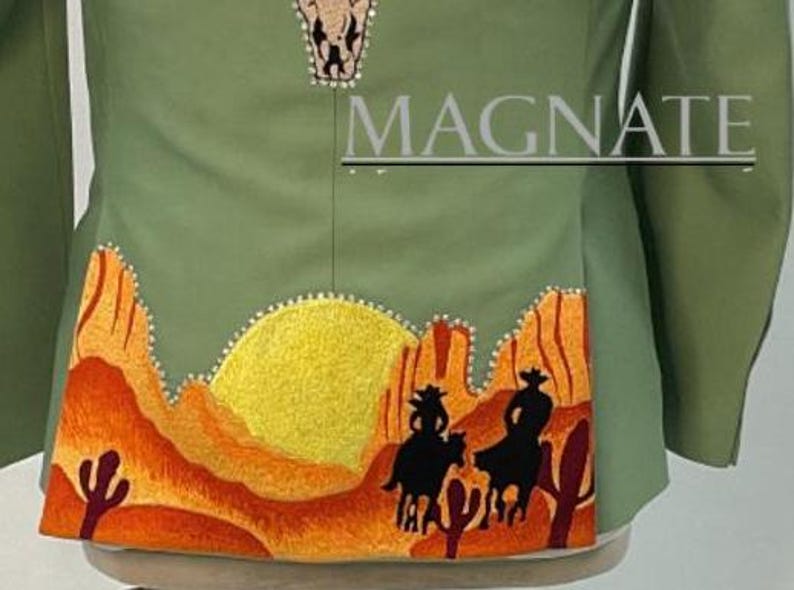 May include: Olive green jacket with embroidered desert scene featuring cowboys, cacti, and a yellow sun. The word "MAGNATE" is printed on the jacket. The jacket has a decorative pattern at the top.