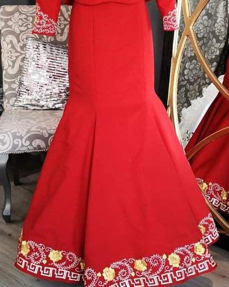 May include: A red mermaid-style skirt with gold and white embroidery around the hem. The skirt is made of a smooth fabric and has a fitted waist.