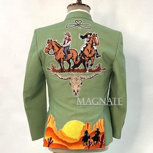 May include: Sage green blazer with elaborate embroidery featuring cowboys on horseback, a desert landscape, and a bull skull. The word "MAGNATE" is embroidered on the lower right side of the blazer.