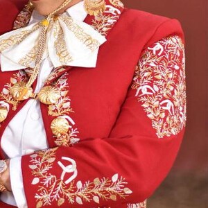 May include: A red embroidered jacket with gold and white thread. The jacket has a white shirt underneath and a white bow tie with gold embroidery.