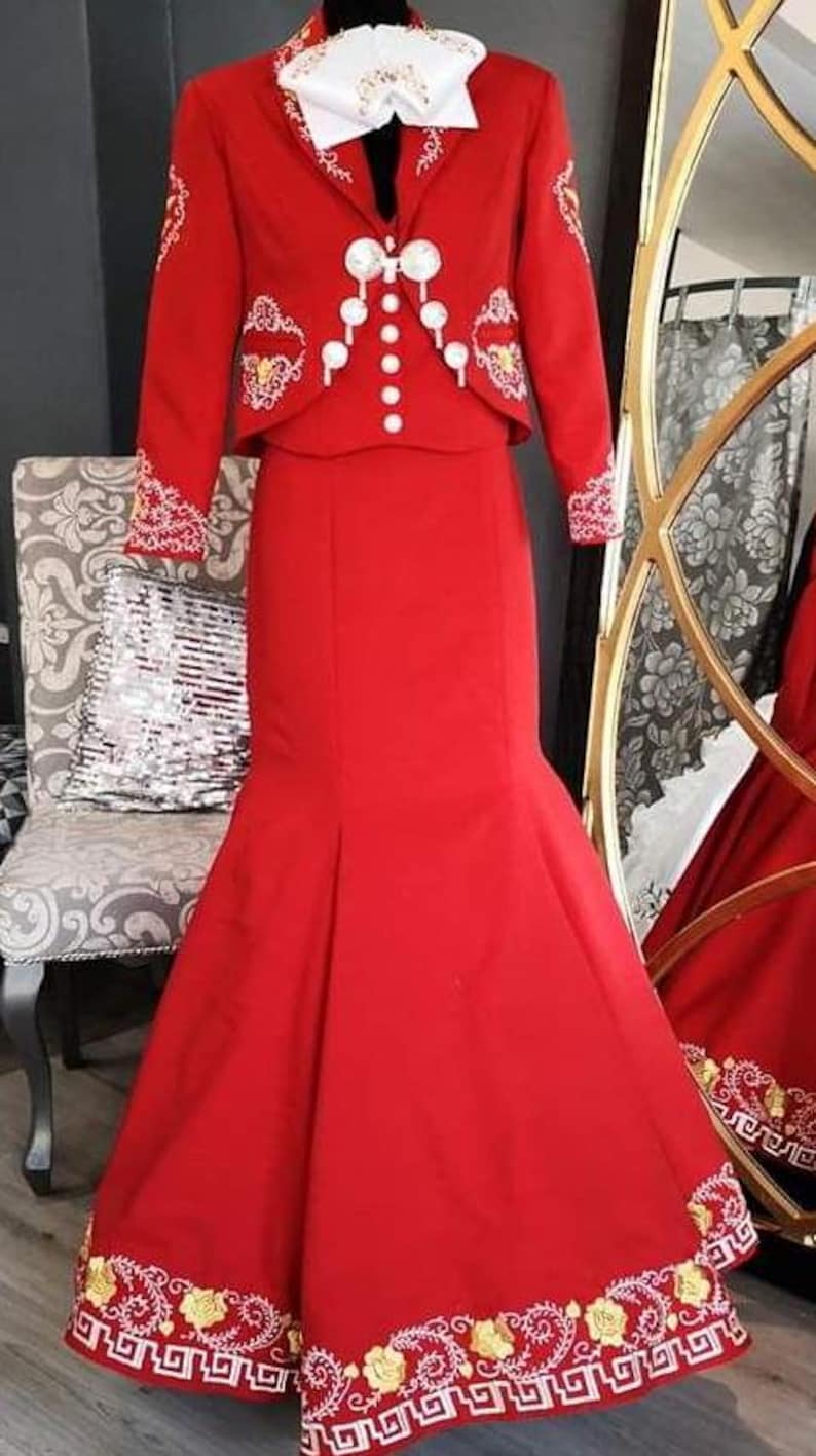 May include: A red dress with a matching jacket, both featuring gold and white embroidery. The dress has a fitted bodice and a flowing skirt with a mermaid silhouette.